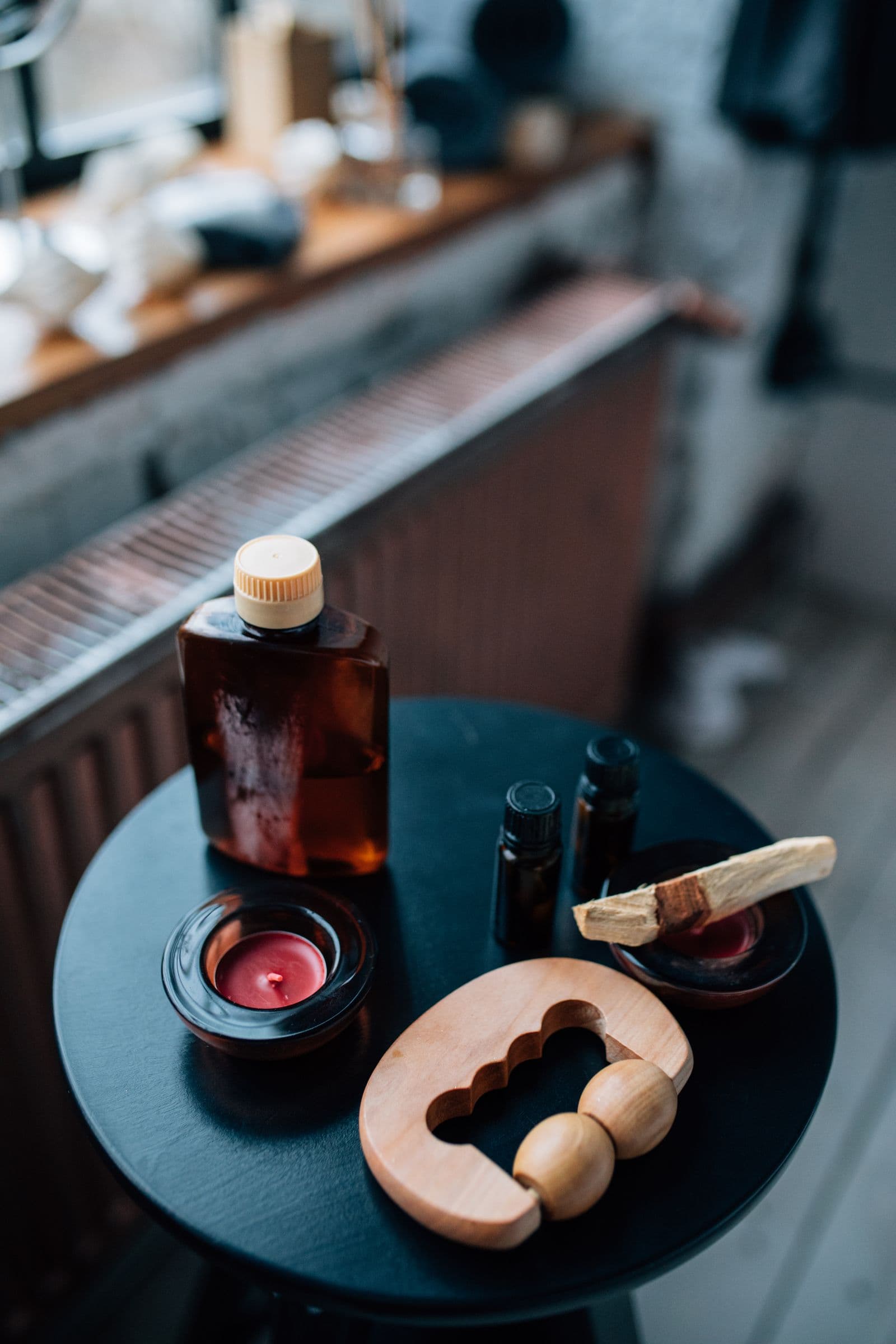 Massage oil, a candle, and a wooden massage tool on a small table